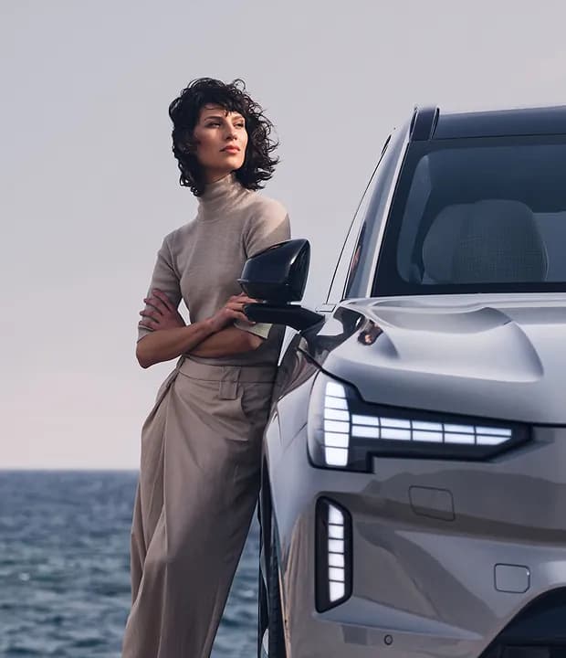 Mulher apoiada em um Volvo com vista para o mar